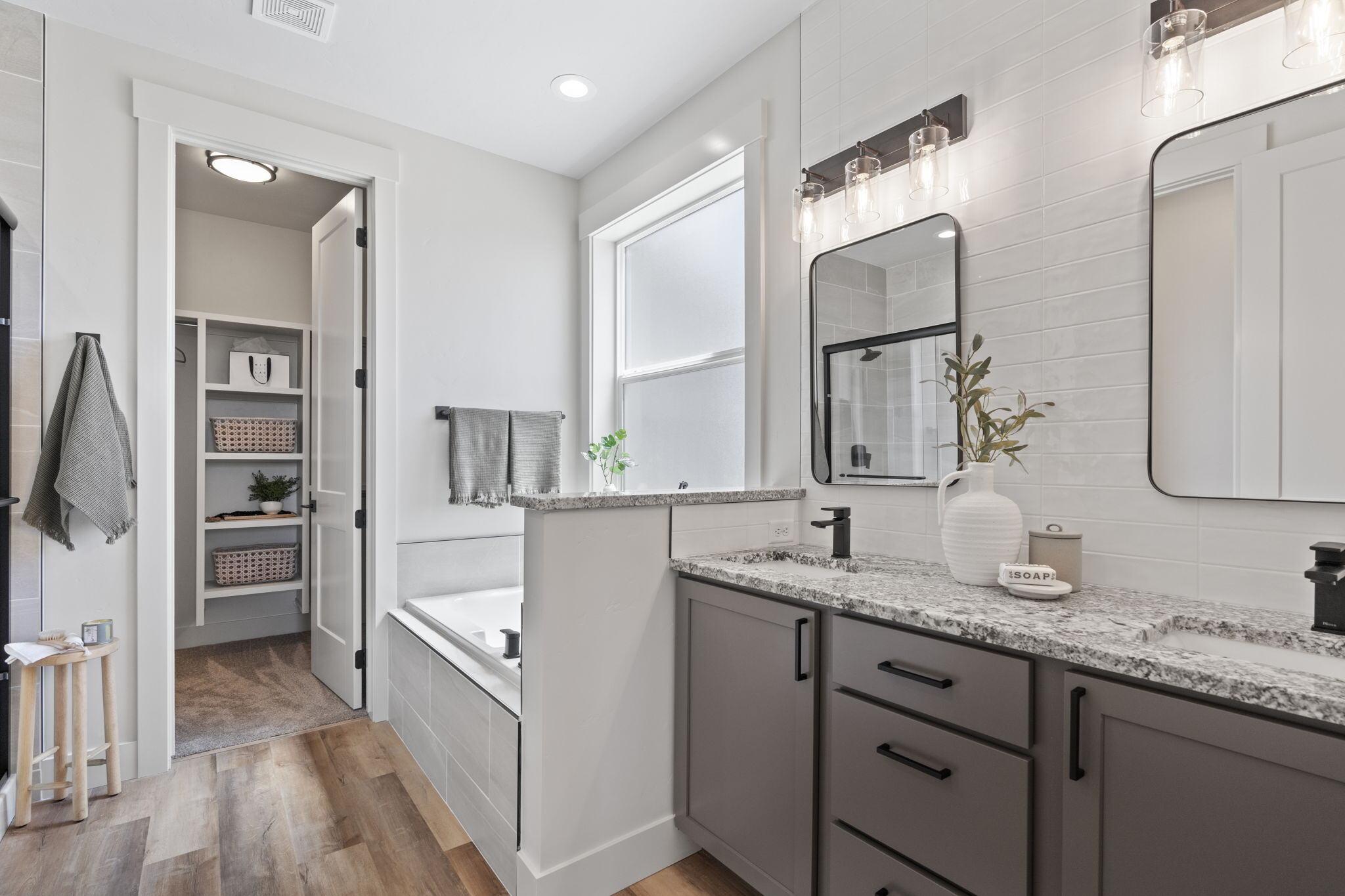 Primary bathroom with a double granite vanity, soaking tub and tiled walk-in shower