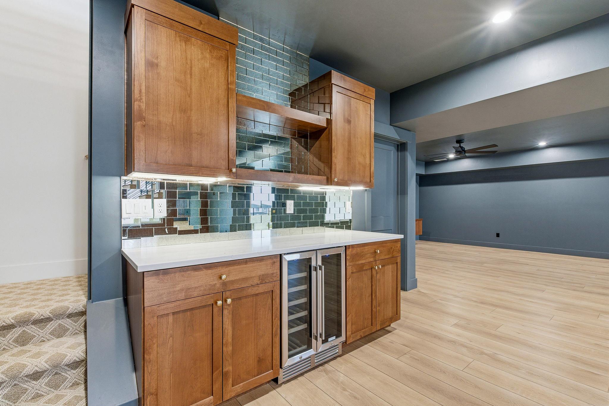 The basement wet bar: mirrored tile backsplash, alder cabinetry, and a glass front beverage fridge