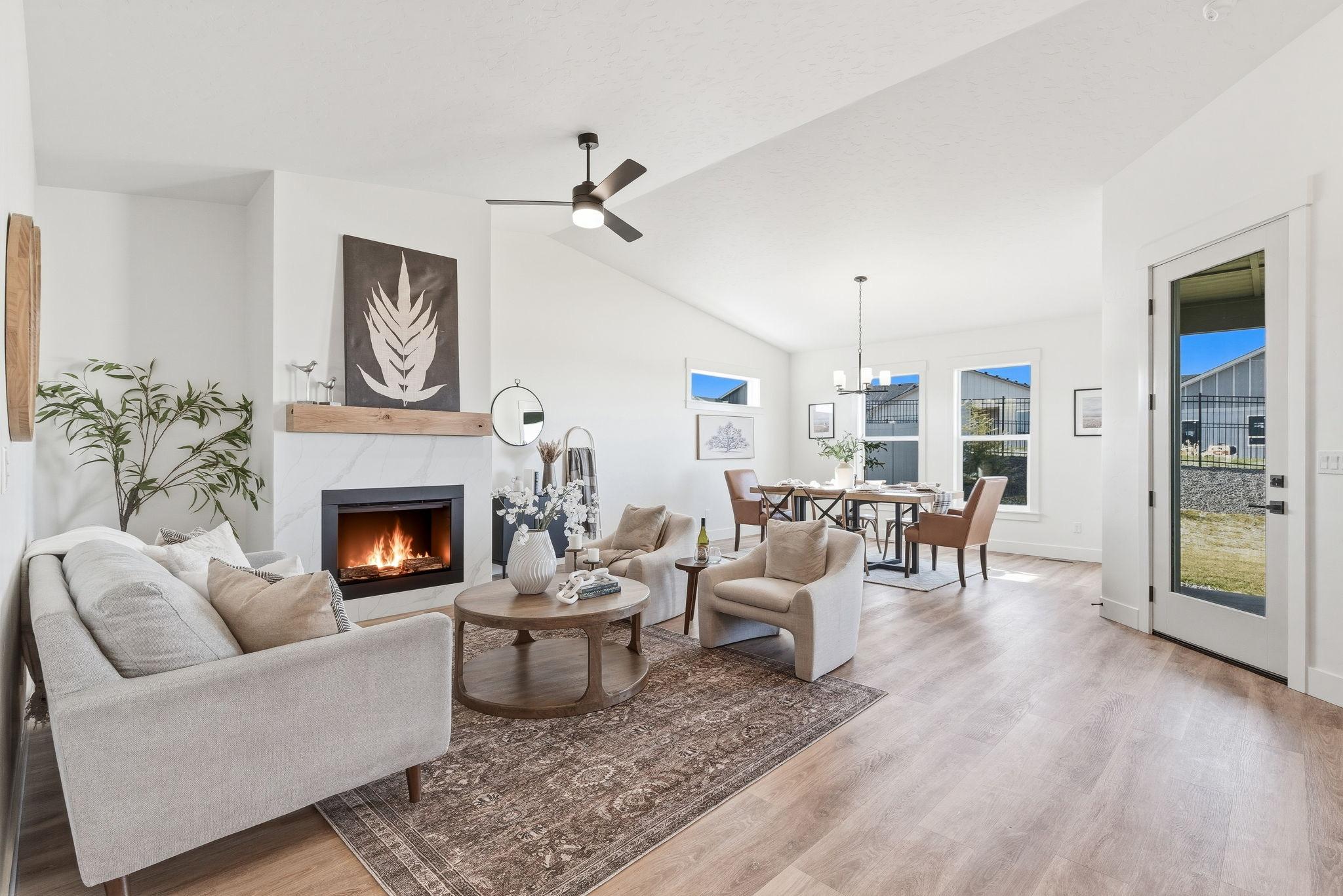 The vaulted great room with a marble fireplace, wood mantel, and the dining area beyond