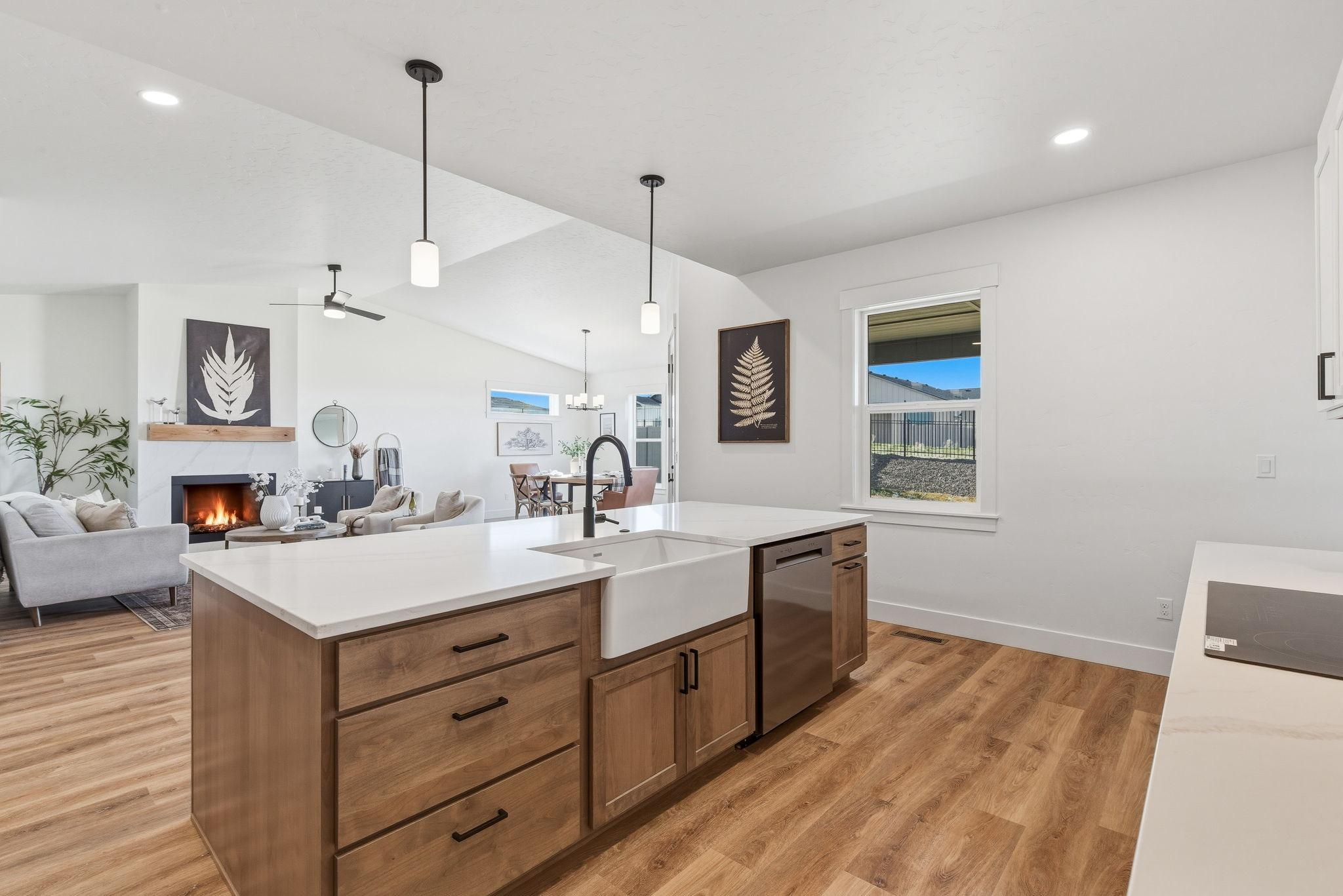 The kitchen island with a farmhouse sink and quartz counters, looking through to the great room fireplace
