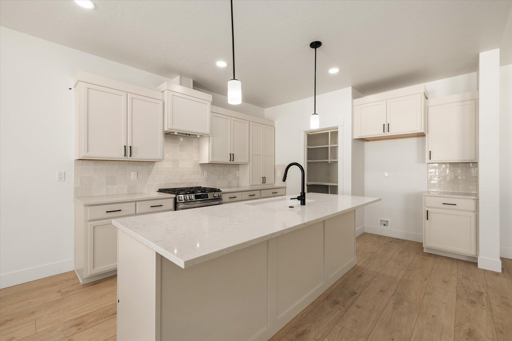 Kitchen with custom Huntwood cabinetry, a quartz island and a freestanding range