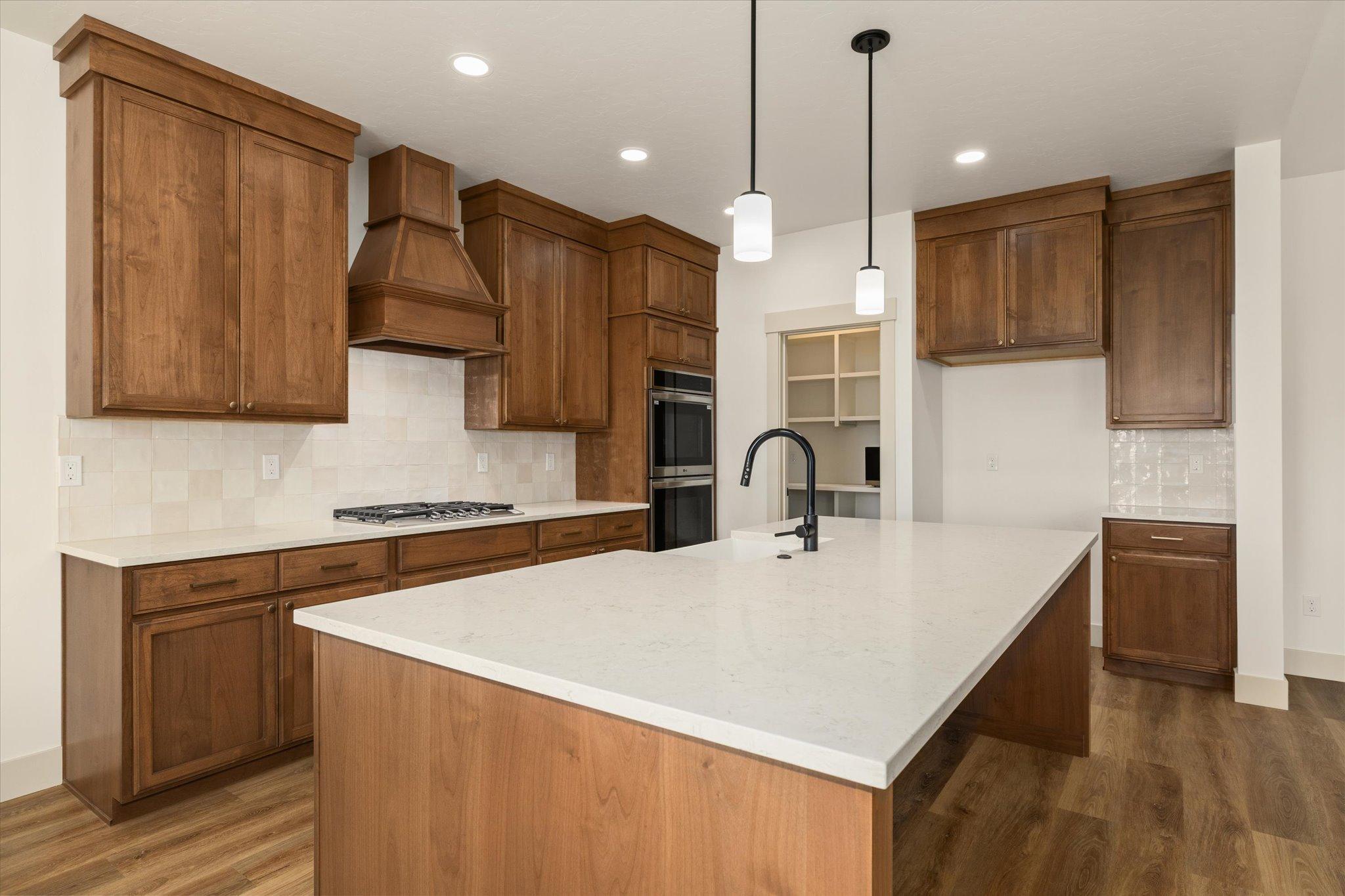 Kitchen with custom Huntwood cabinetry, a quartz island and stainless steel appliances