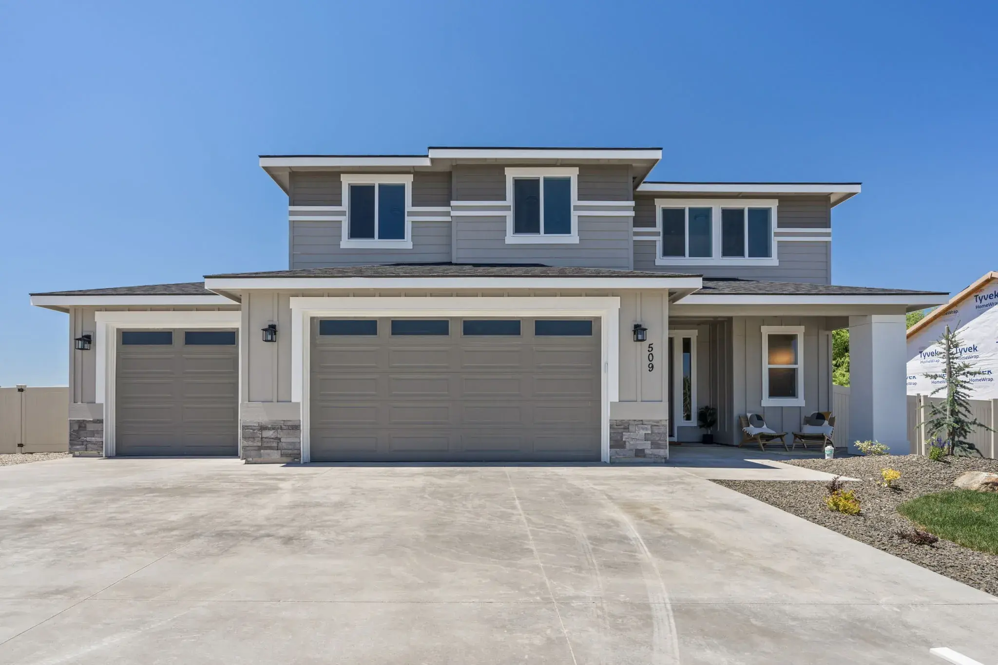 The front of Harvest Creek Vaulted Home in New Plymouth, Idaho: a two-story Bear Homes build with a three car garage and stone accents