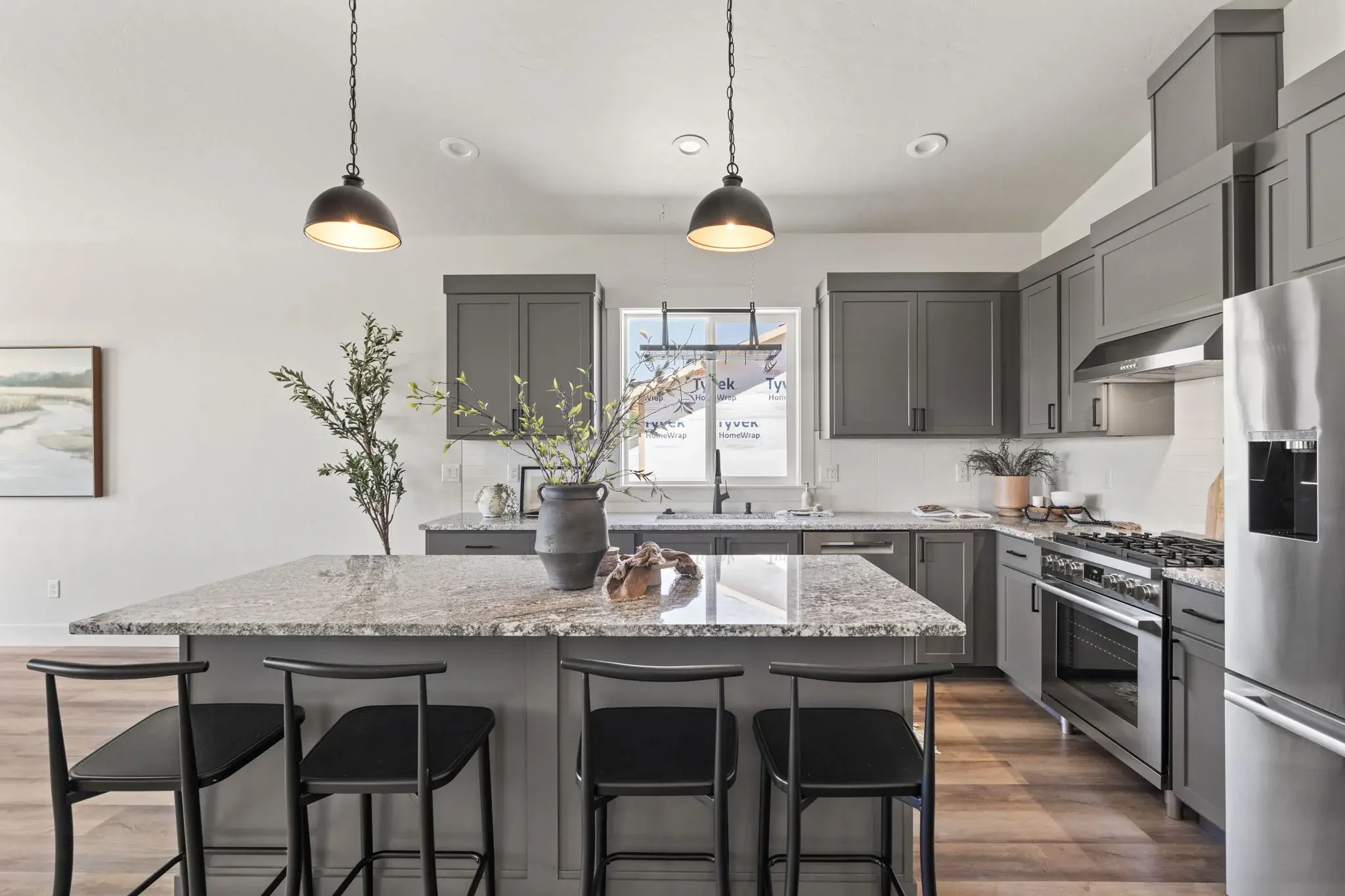 The kitchen at Harvest Creek Vaulted Home with a granite island seating four, grey shaker cabinetry, a gas range and stainless appliances