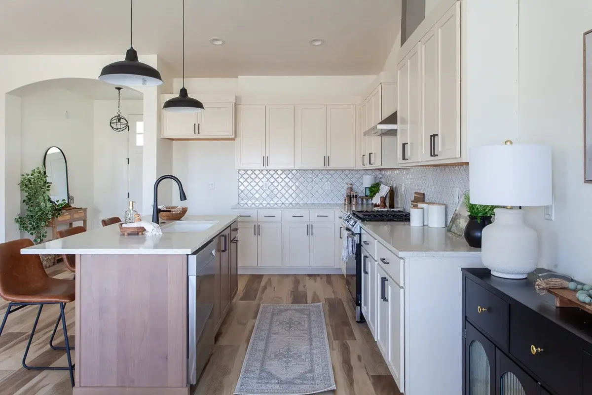 Kitchen island with seating for three, arabesque tile backsplash and black farmhouse pendants in a Bear Homes build
